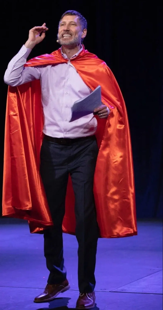 a man in a red cape standing on a stage