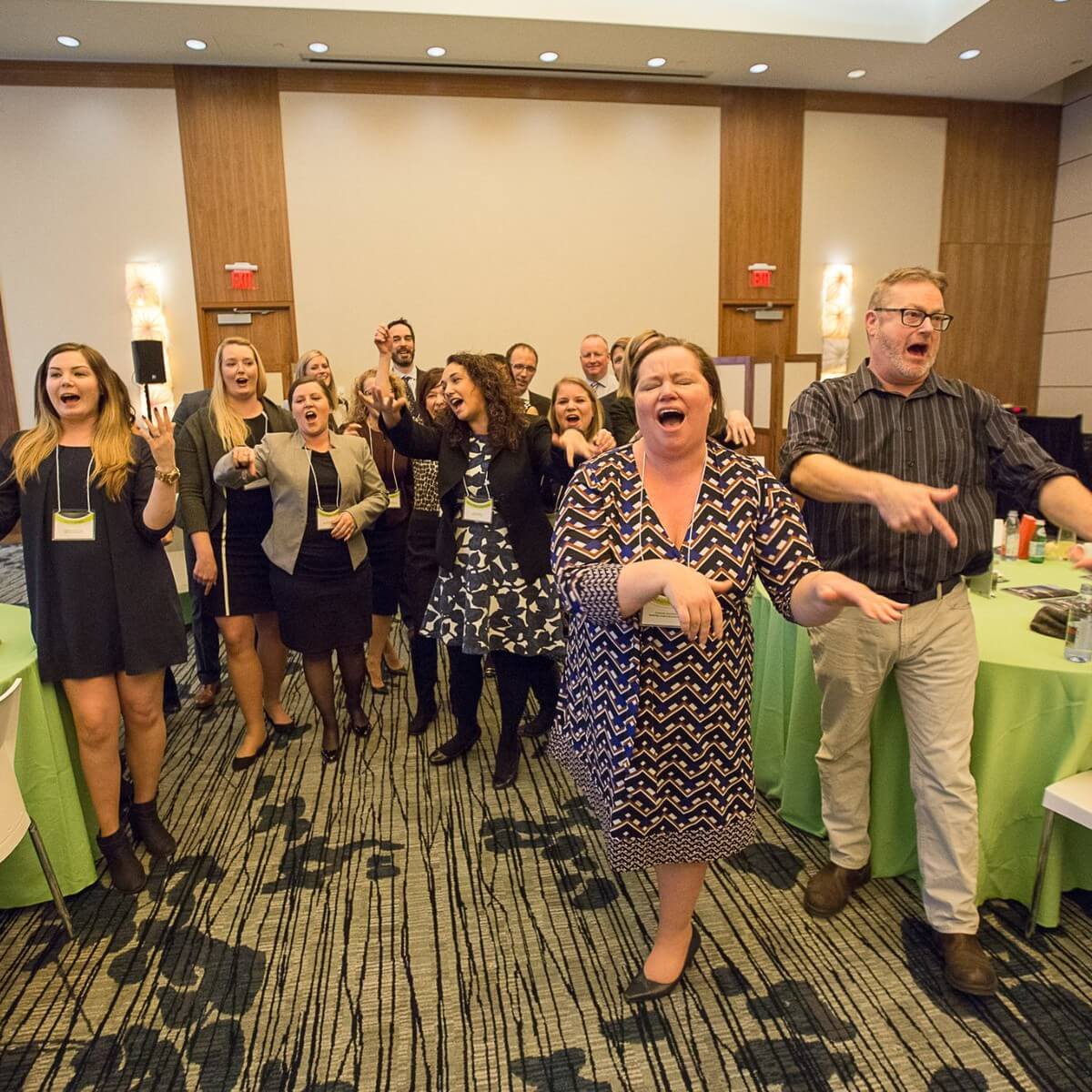 Corporate audience laughing and pointing during an Engagement Unlimited Improv Comedy show at a company party