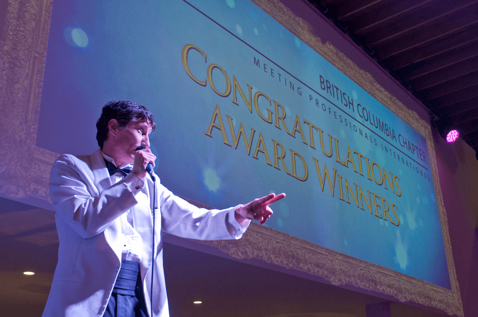 Professional emcee on stage at a corporate gala running the evening for an Engagement Unlimited client