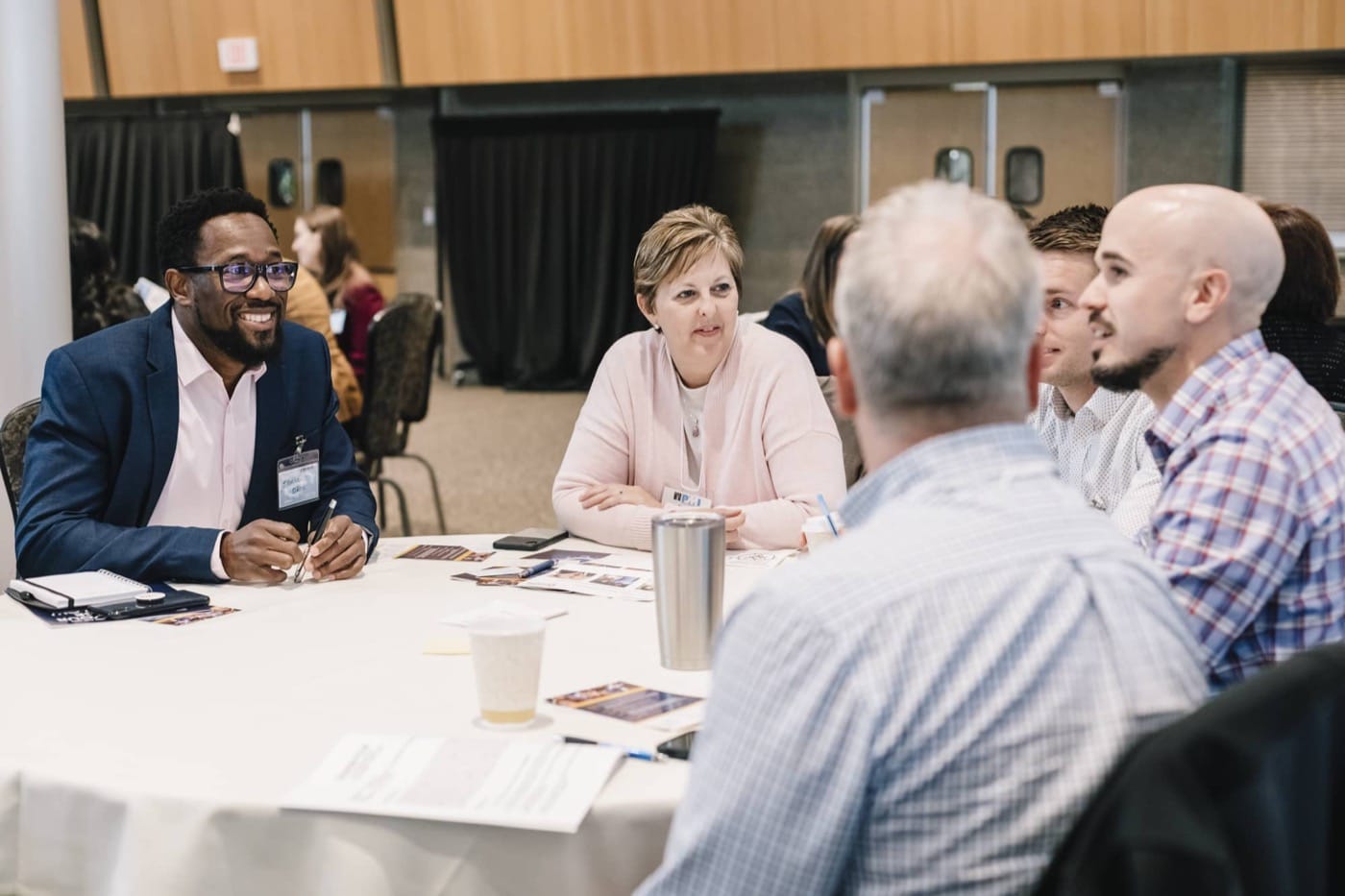 Workshop participants seated at tables talking with each other during connection time at an Engagement Unlimited facilitated session