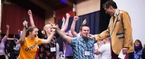 A crowd cheering and raising hands during Name That Tune