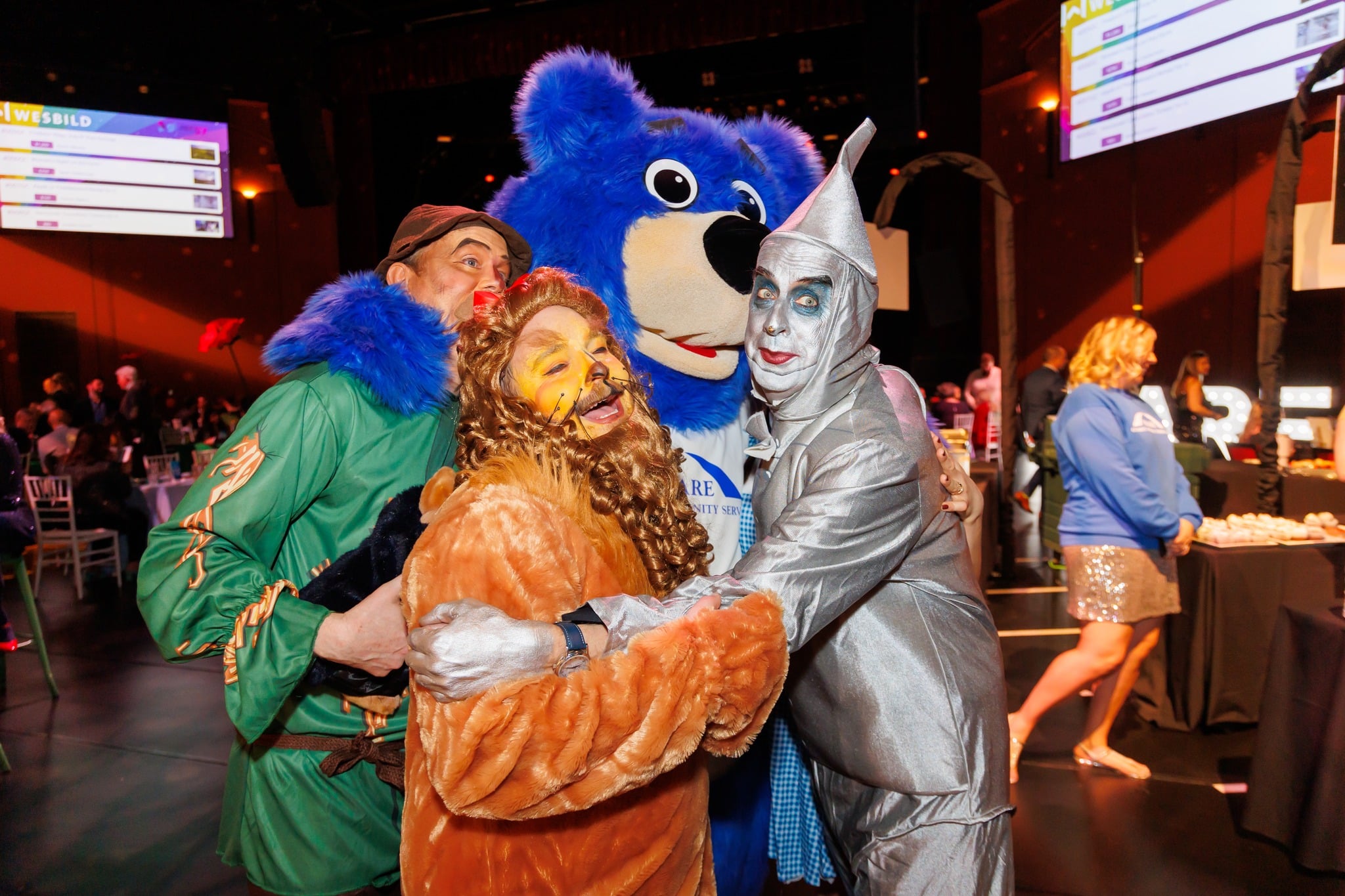 A branded client mascot poses with roving costumed characters
