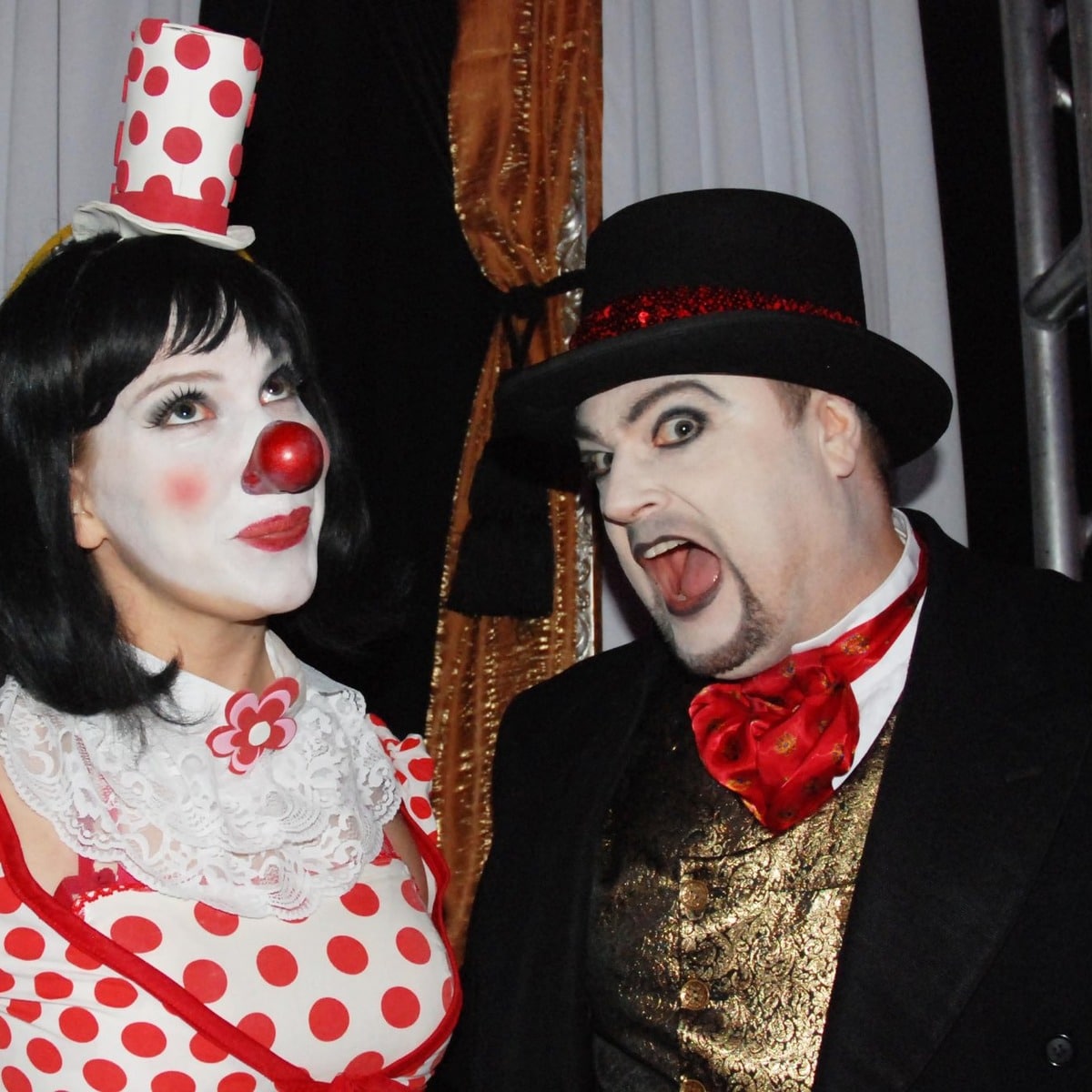 A Cabaret-themed musical number on stage, performers in sequined black under the show's big screen