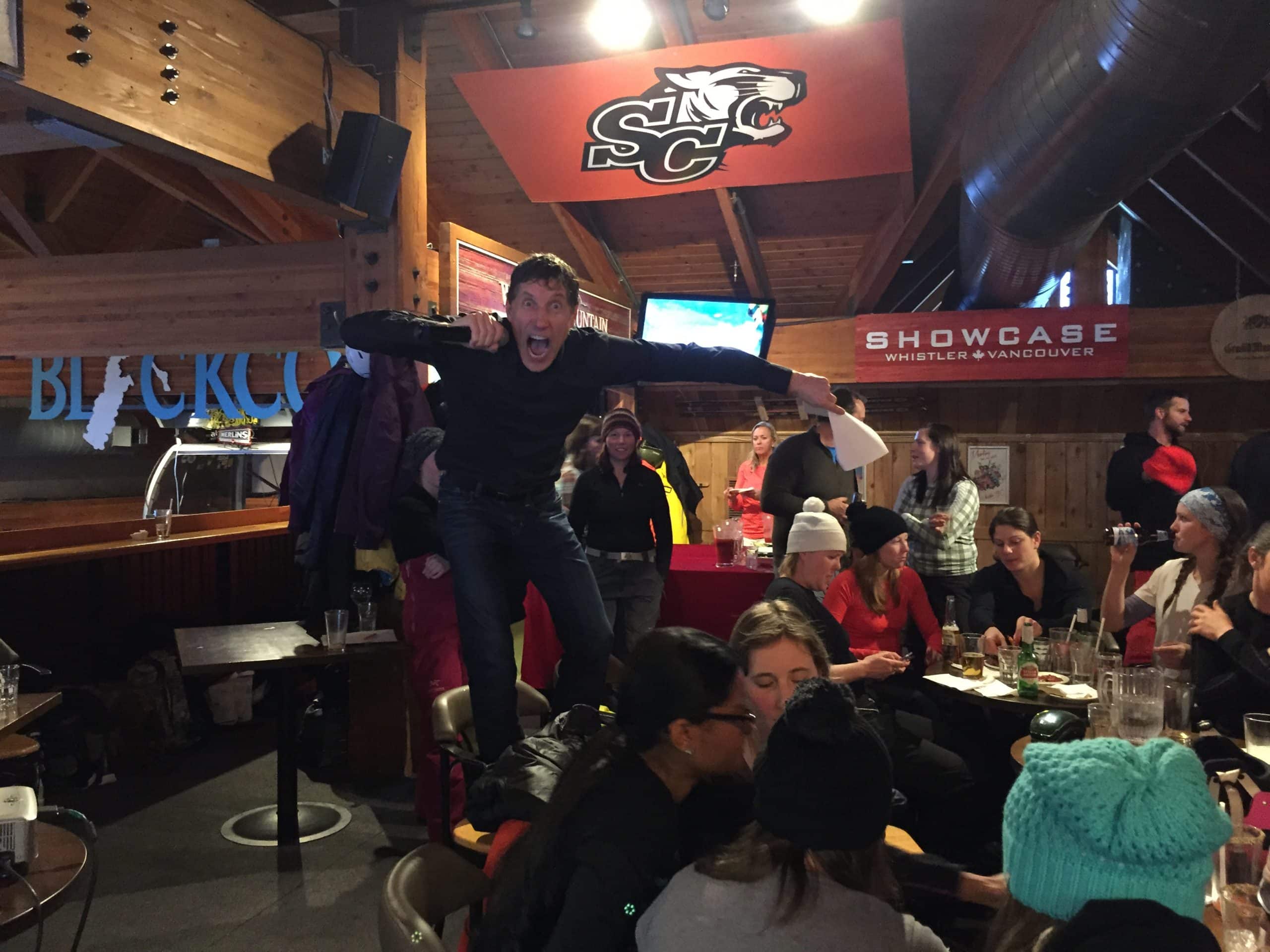 A POP Trivia host fires up the crowd from a barstool at a Whistler après-ski trivia night