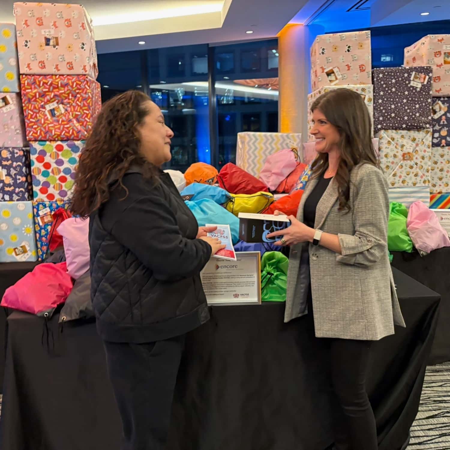 Volunteers hand off assembled Kindness Kits to the charity partner