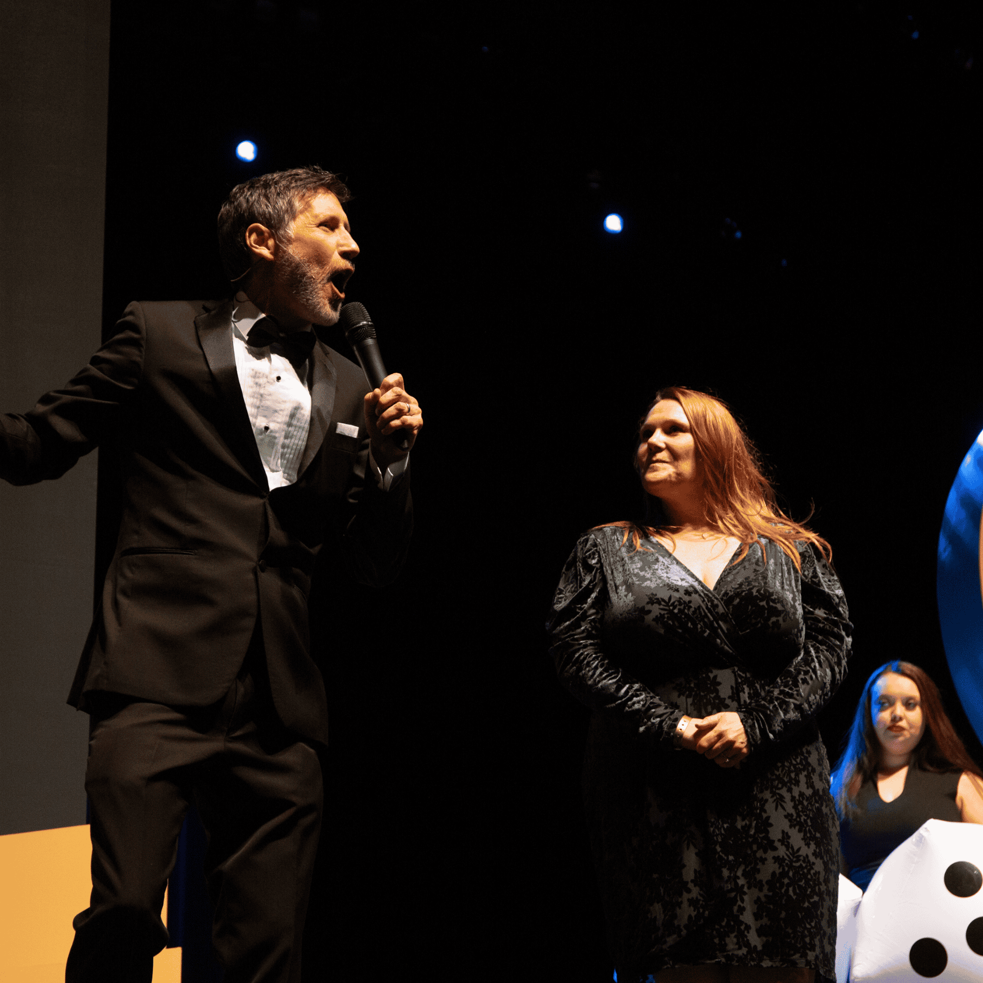 Roger emcees a Coast Capital event in a tuxedo on stage