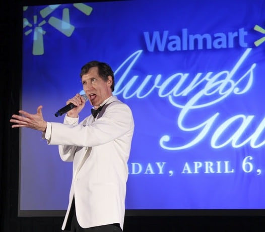 Roger hosts the Walmart Awards Gala, addressing the room from center stage