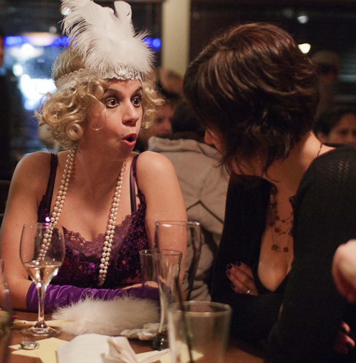 A costumed flapper suspect reacting mid-conversation with a guest at an Engagement Unlimited Murder YOU Mystery