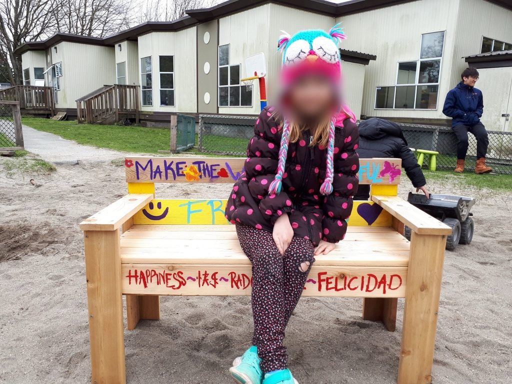 A child enjoys the finished Buddy Bench