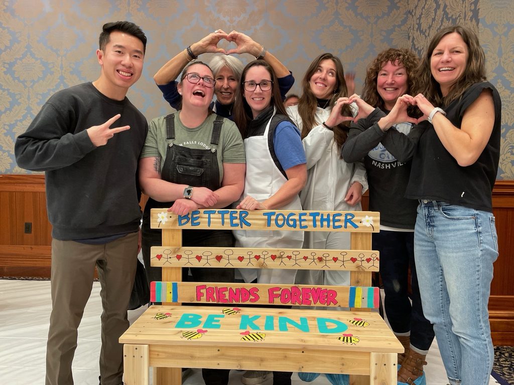 Participants laugh together while building a Buddy Bench