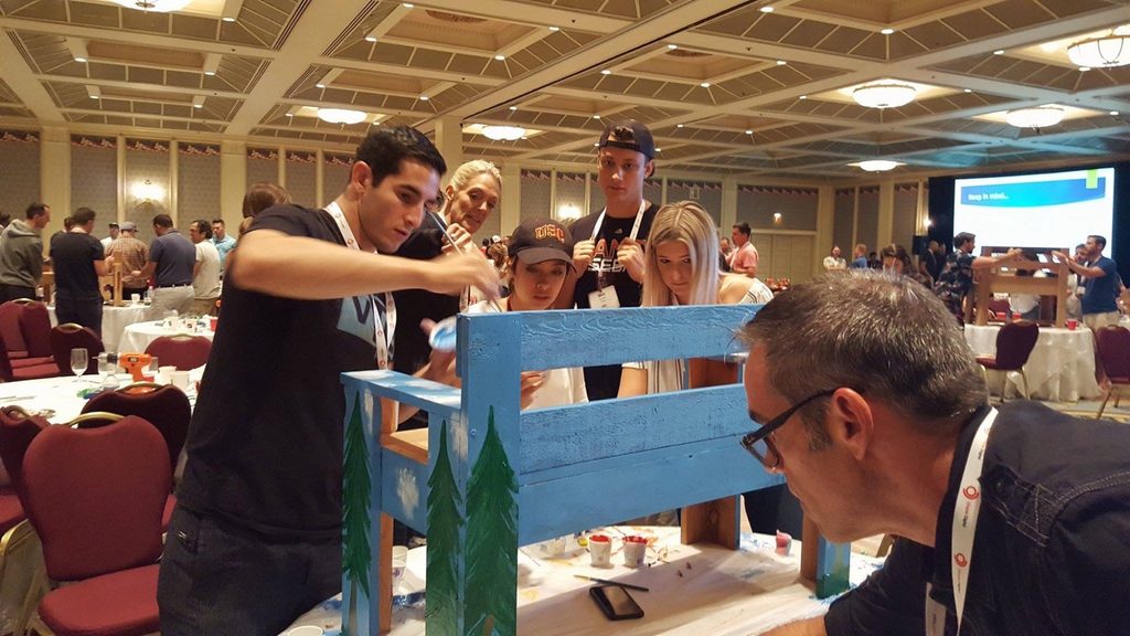 Employees paint and assemble a Buddy Bench during a corporate build event.